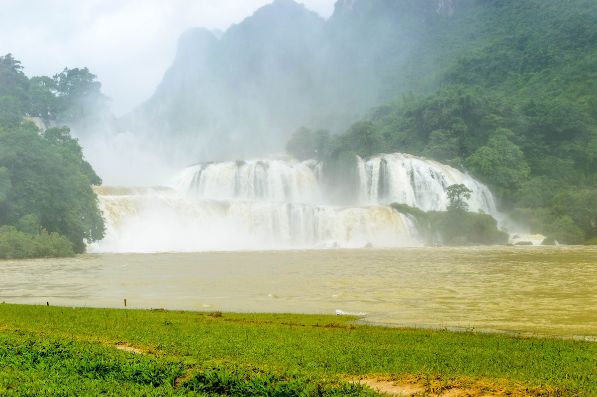 De Ban Gioc Waterval met veel bruin water na regen, gehuld in nevel