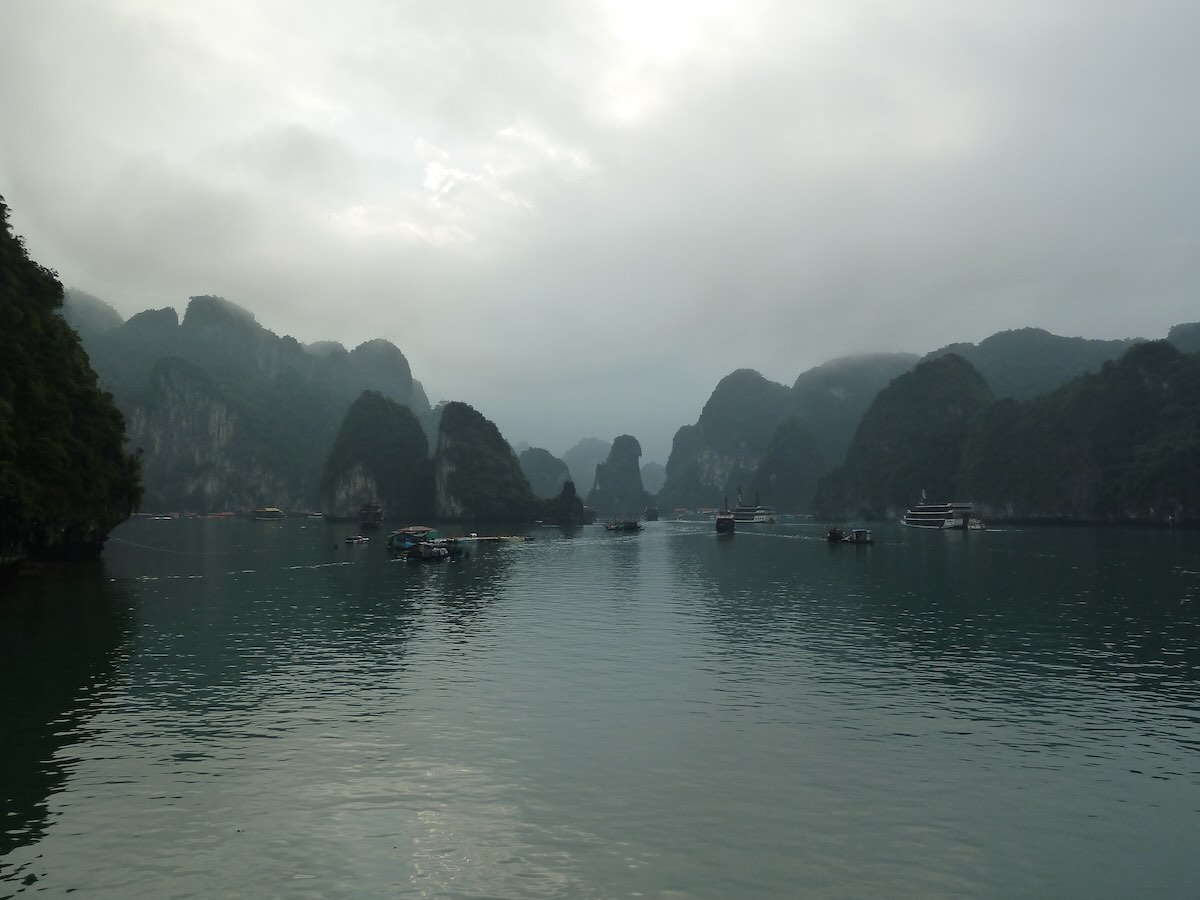 Cruiseboten varen door een doorgang tussen de kalksteenrotsen van Ha Long Bay