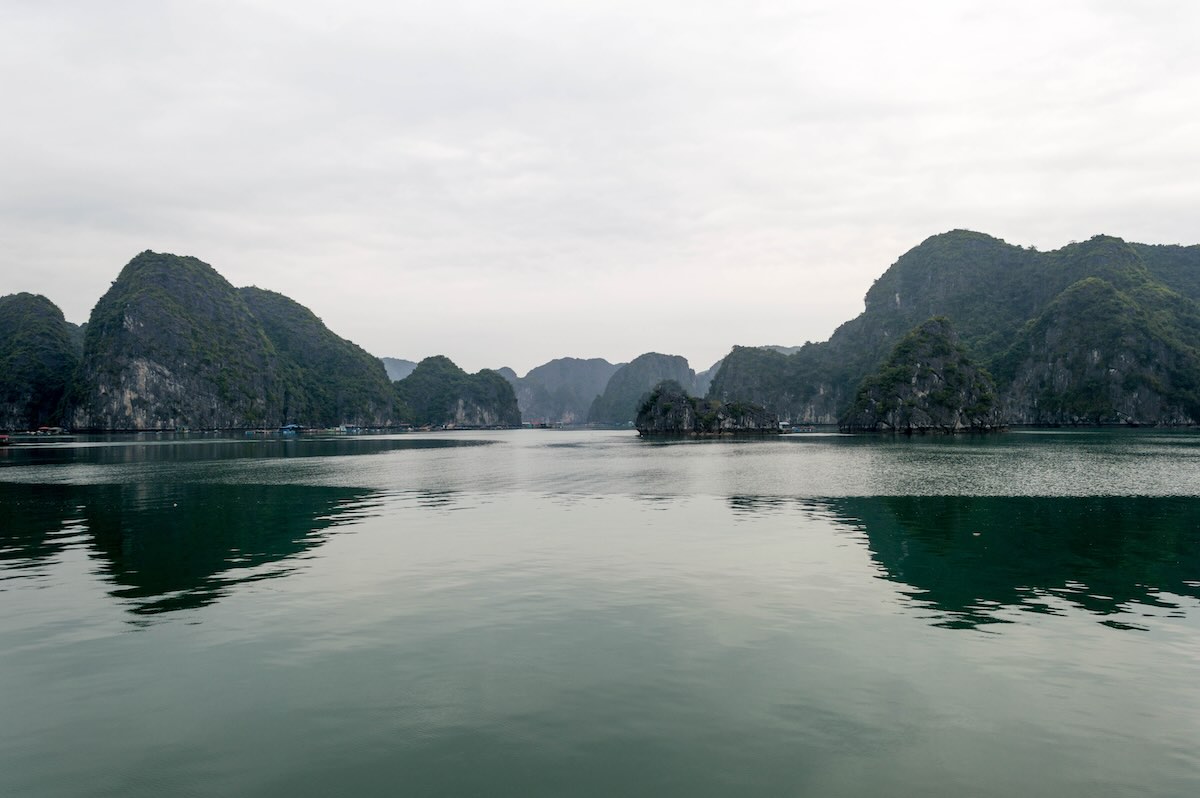 Kalksteeneilanden die weerspiegelen in het water van Ha Long Bay