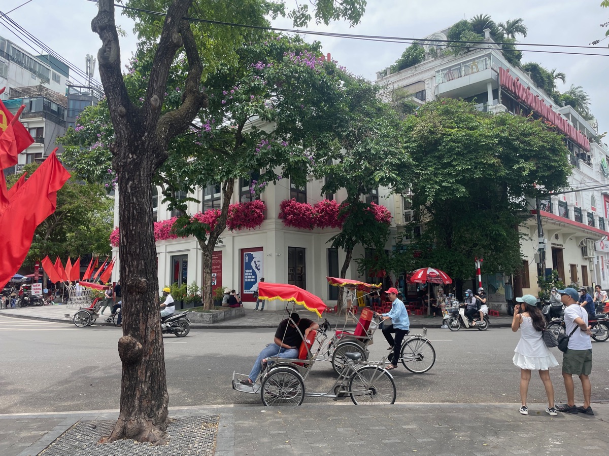 Cyclos en scooters op een kruispunt in het centrum van Hanoi