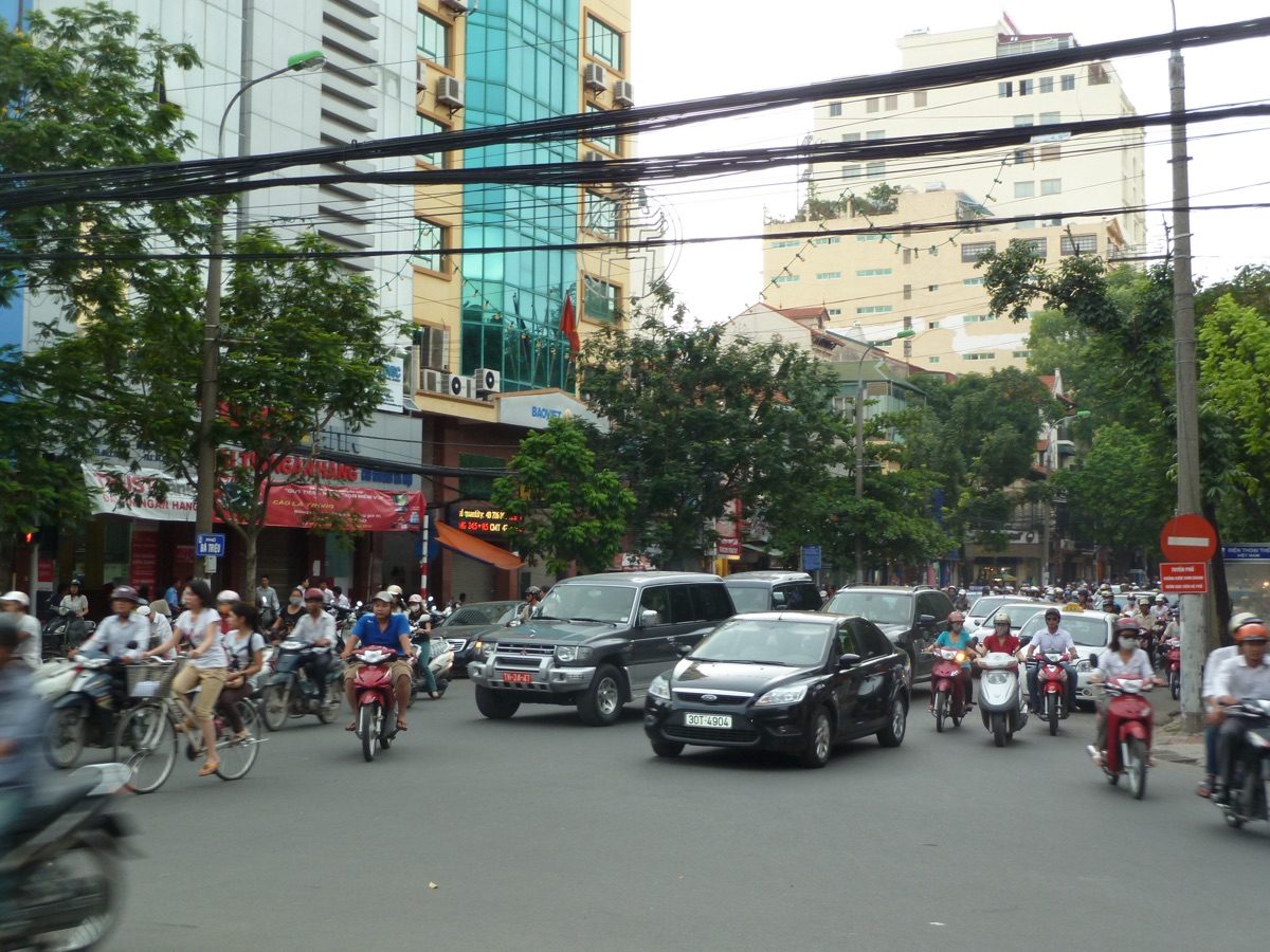 Scooters, fietsers en auto's in een drukke straat in Ho Chi Minh City