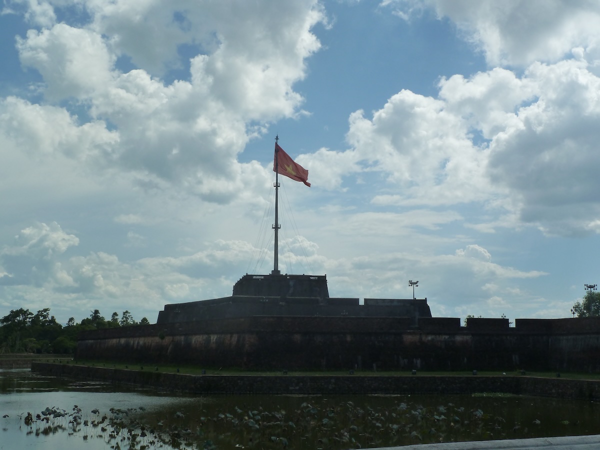 De vlaggentoren van de citadel van Hue met de Vietnamese vlag, achter de slotgracht