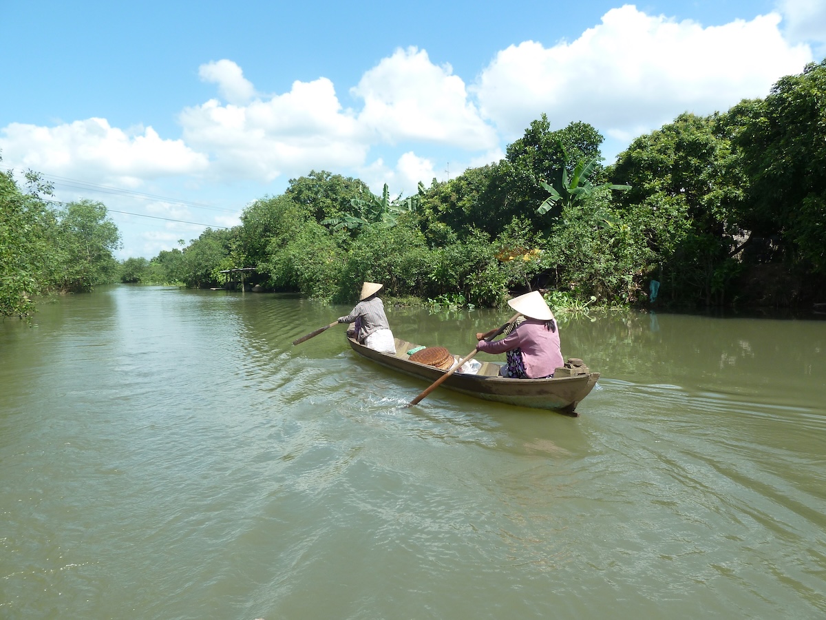 Twee vrouwen roeien met een bootje door een kanaal in de Mekong Delta